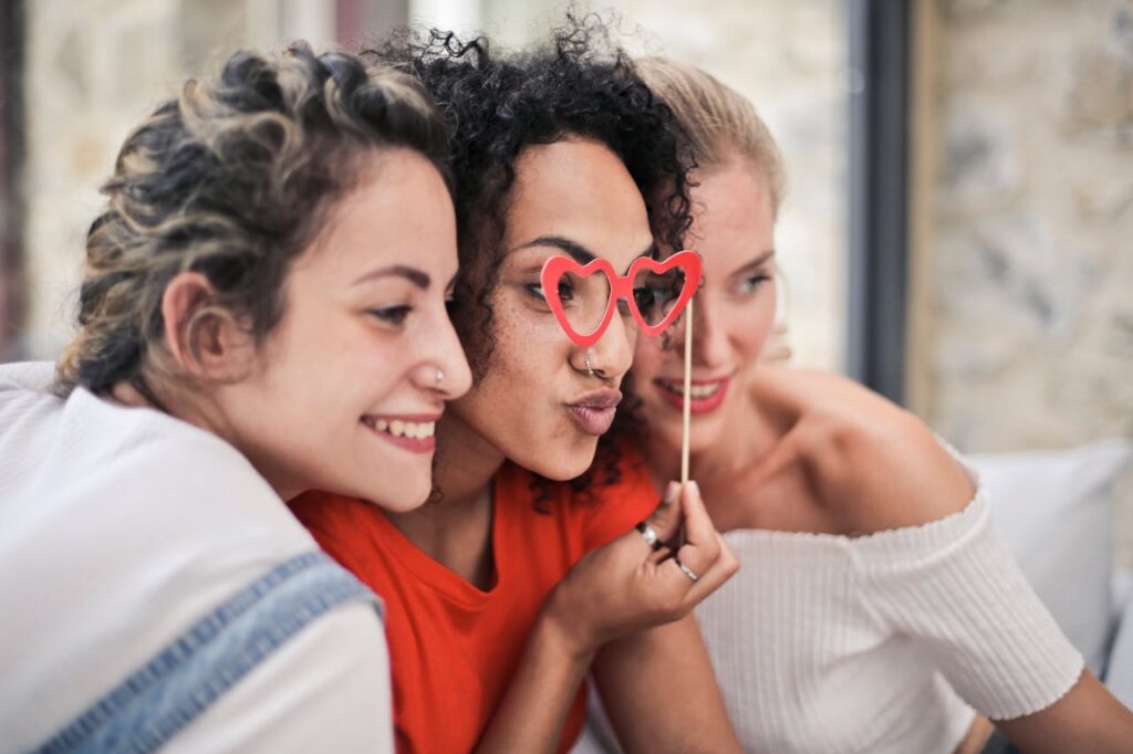 pexels photo 1524105 Three women enjoying a playful moment with heart-shaped glasses, symbolizing friendship and fun.